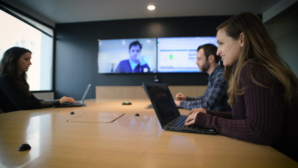 People at conference table video conferencing